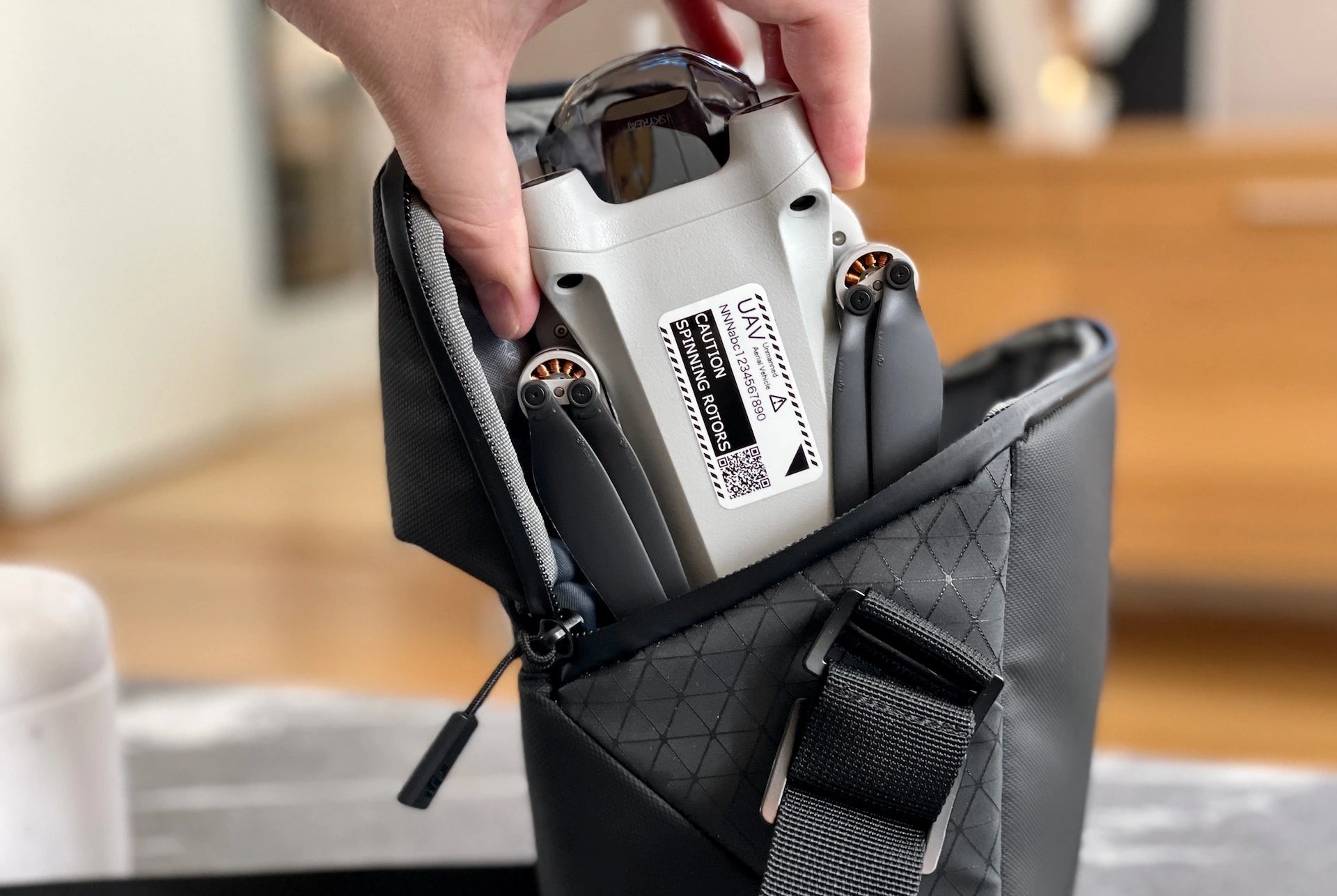 Hand holding a small drone inside a black bag with a blurred background